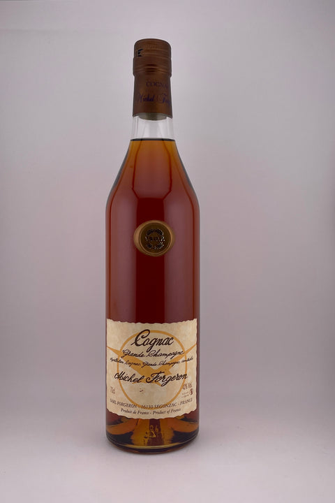 A bottle of Michel Forgeron VSOP Cognac with a golden amber colored liquid inside. The label has intricate details and the cap is dark.