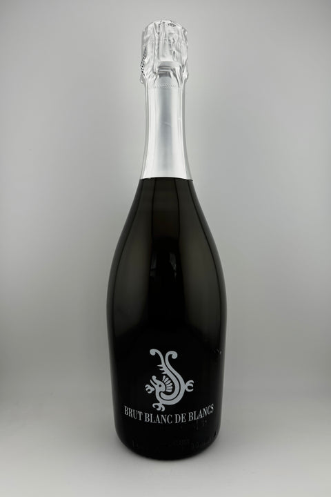 A bottle of Blanc de Blanc, Moulin de la Roque, Mousseux with fine bubbles visible on the surface.