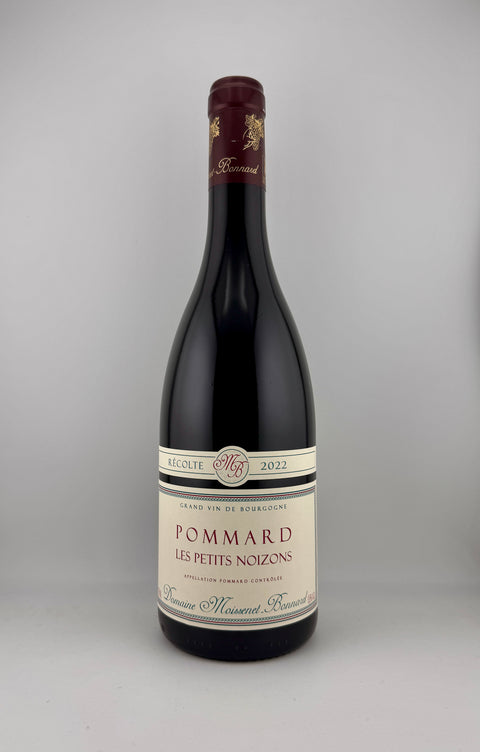A bottle of Pommard Les Petits Noizons red wine from the domaine Maison Robert Pérignon, featuring a dark glass bottle, cream-colored label, and dark red wax seal on a neutral gray background.