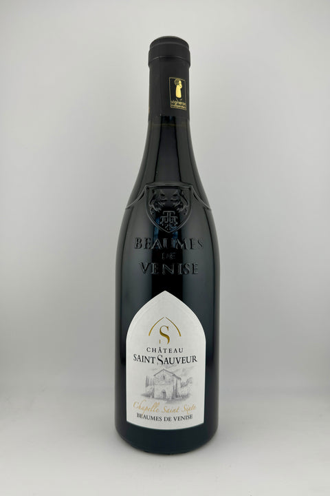 A bottle of Chapelle Sixte, Château St Sauveur, AOC Beaumes de Venise, 2023 wine with a white label and a view of the wine inside the bottle.