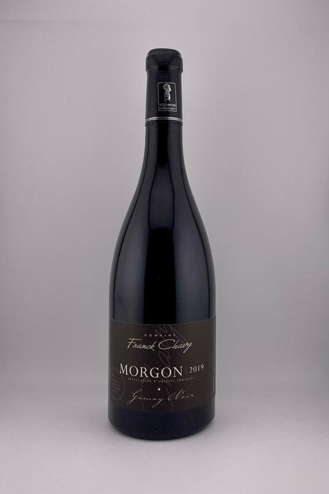 A bottle of Domaine Franck Chavy Morgon wine, 2019 vintage, with a dark label and red wine visible inside.