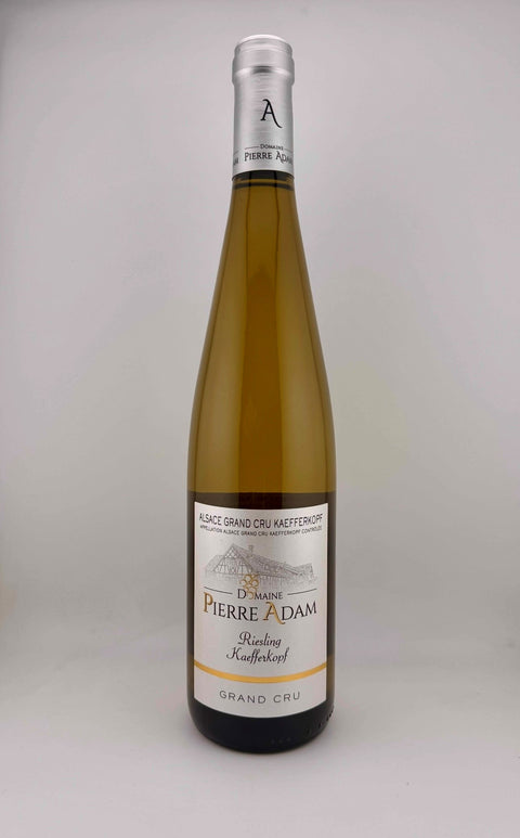 Bottle of Domaine Pierre Adam Riesling 1er Grand Cru wine with a light yellow label and bright green highlights.White wine.