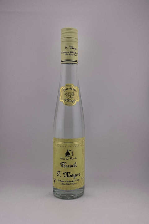 A bottle of Kirsch Eau de Vie brandy with a yellow label and a cap, against a plain background.