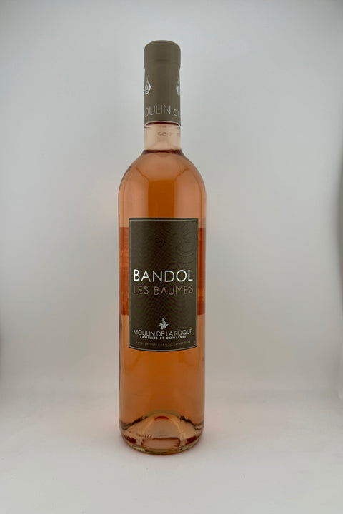 A bottle of Les Baumes, Moulin de la Roque, AOC Bandol, with a pink hue and a label that includes the brand name 'Bandol' and the grape variety 'Moulin'.