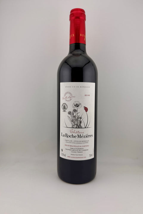 A bottle of Cháteau La Roche Meziéres wine with a red cap and label featuring artwork and text.