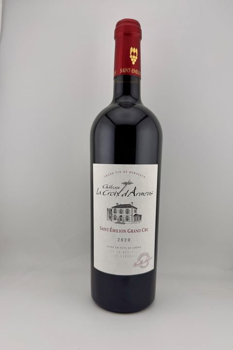 A bottle of Cháteau La Croix d'Armens, St-Emilion Grand Cru, 2020 wine with a red cap and label.